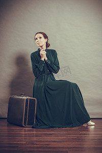 妇女复古风格长深绿色礼服与旧行李箱，复古照片