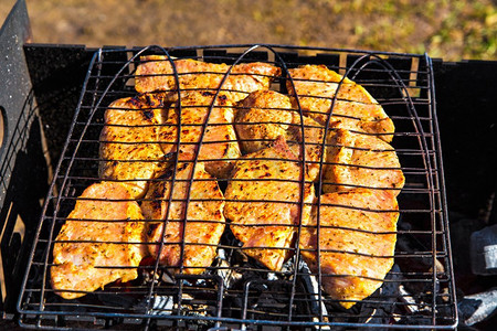 beaf摄影照片_腌猪肉辣牛排在braai烤。烧烤与美味的肉在烤架顶视图。户外季节烹饪假期野餐。
