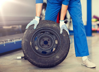 汽车服务、维修、保养和以人为本的理念--车间里车轮轮胎的汽车机械师。汽车车间里的轮胎工