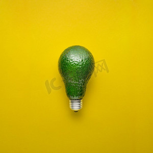 水果的创意摄影照片_黄底牛油果作为电灯泡的创意概念照片。