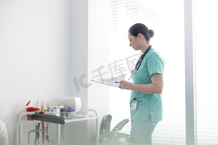 中年成人护士在医院检查剪贴板上的医疗报告