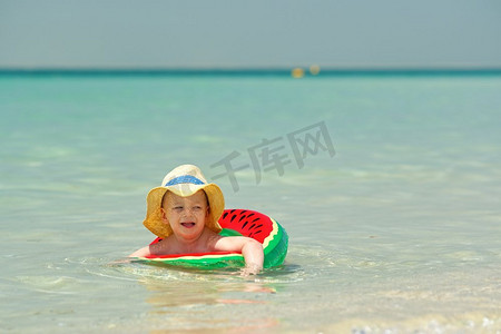 幼儿游泳摄影照片_海滩上戴着充气游泳圈的两岁幼儿