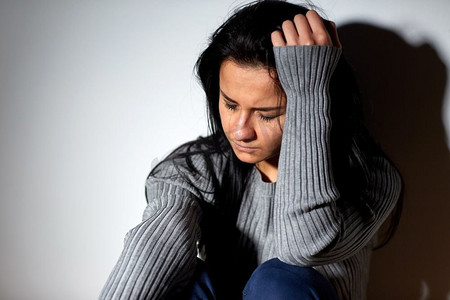 人、悲伤和家庭暴力的概念--不快乐的女人坐在地板上哭泣。不开心的女人在地板上哭