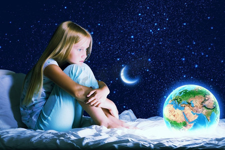 晚安海报星空摄影照片_晚安。女孩坐在床上做梦。这张图片的要素由美国宇航局提供