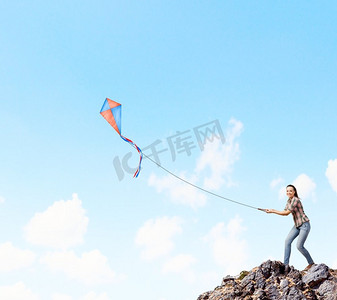 拿着风筝的女人。年轻漂亮的女人站在岩石上，放着五颜六色的风筝
