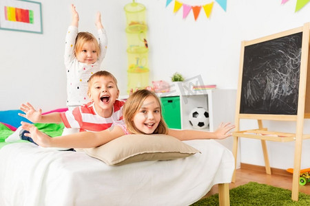 童年，休闲和家庭概念—快乐的小孩子在家里的床上享受乐趣。快乐的小孩子在家里的床上玩得开心