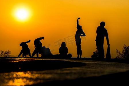 日落时分在海滩上练习瑜伽的人群剪影