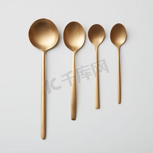 一系列金色的餐具。灰色背景上的一套四个不同的金汤匙。灰色背景上的一系列金色餐具。