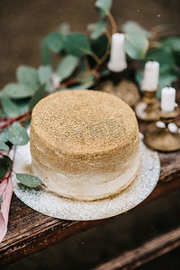 金色婚礼装饰摄影照片_婚礼装饰，在瀑布的背景下，木凳上有一个金色的蛋糕