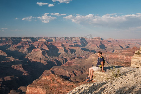 游客与背包在大峡谷坐在岩石边缘，亚利桑那州，美国