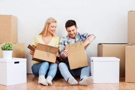 抵押贷款，搬家和房地产概念—快乐的夫妇开箱箱在新家。快乐的夫妇开箱箱在新家