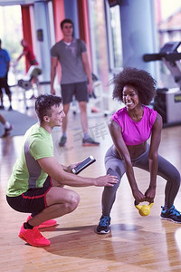 健康的年轻夫妇在CrossFit健身房和私人教练一起锻炼举重。在CrossFit健身房与私人教练一起进行举重锻炼