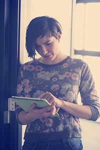 一位穿着休闲时髦服装的年轻女商人在现代创业公司商务办公室内部的平板电脑上工作