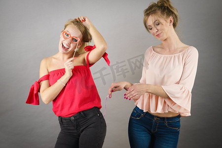 两个快乐的朋友女人拿着狂欢节的饰品在派对上玩得很开心拿着狂欢节饰品的妇女们