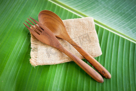 木勺子和叉子厨房用具设置在袋香蕉叶背景/零浪费使用较少塑料概念