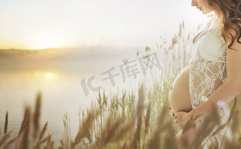 等待日出摄影照片_走在清新的夏日草地上的孕妇