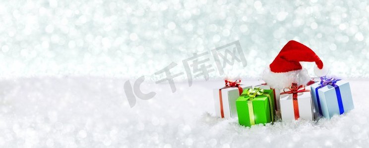 有小礼物和雪地圣诞老人帽子的圣诞节日贺卡。雪地里的圣诞礼物