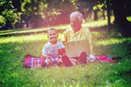 使用平板电脑的祖父和孩子在公园。祖父和孩子在公园使用片剂