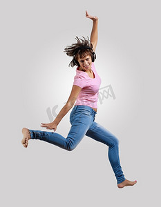 年轻女子又跳又跳。非常现代、苗条的嘻哈风格的女人在灰色的背景上跳着舞