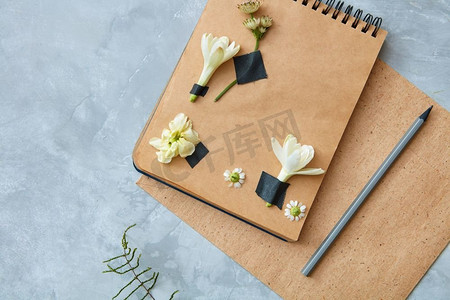 工艺笔记本顶视图与花装饰与铅笔在具体背景，俯视图.纸上的花卉装饰
