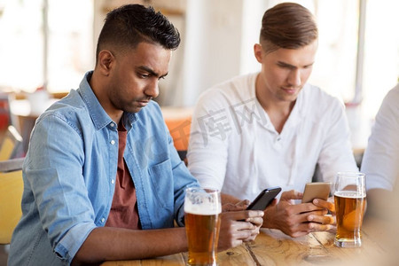 人和科技概念-男性朋友带着智能手机在酒吧或酒吧喝啤酒。男性朋友拿着智能手机在酒吧喝啤酒