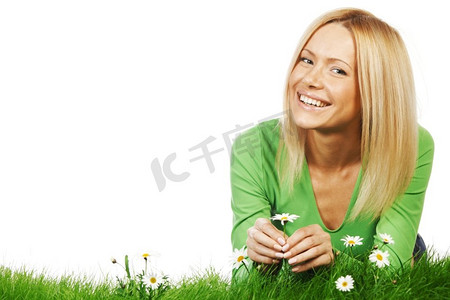 快乐的年轻女子躺在开着洋甘菊的草地上，孤立在白色的背景上。带花的草地上的女人