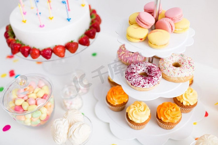 吃蛋糕摄影照片_派对食品和节日概念—不同的甜点和生日蛋糕。生日派对上的食物和饮料
