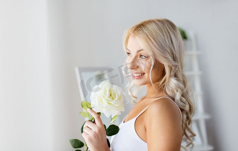 早上和人的概念-穿着白色内衣的漂亮年轻女子在家中的窗户上开着玫瑰花。窗前穿着内裤、手持玫瑰花的女子