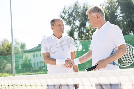 竞争性摄影照片_夏季比赛期间，站在网球场上微笑的男子打招呼