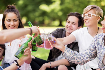 休闲，人，庆祝的概念-快乐的朋友在夏令营碰杯不含酒精的饮料。快乐的朋友在夏季公园碰杯