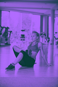 灵活性训练摄影照片_一名女子在健身房为她的训练做伸展和热身。可爱的年轻女子伸展和热身为她的训练在健身房二人组音