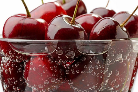 新鲜天然红樱桃在玻璃杯中加水和气泡的宏观照片