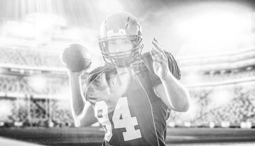 灯光室内背景摄影照片_一名四分卫美式橄榄球运动员在灯光和照明弹的大型现代体育场投球