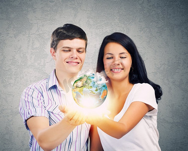 年轻的家庭。一对幸福的年轻夫妇手捧着地球。这张图片的要素由美国宇航局提供