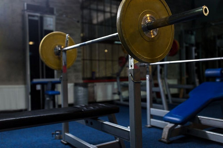 运动、健身和器材概念-健身房内有杠铃的负重板凳。健身房提供带杠铃的举重椅