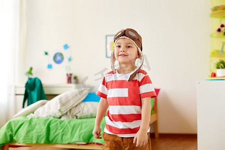 ui游戏框摄影照片_童年，想象力和梦想的概念--快乐的小男孩戴着飞行员帽在家玩游戏。戴着飞行员帽的快乐小男孩在家里玩耍