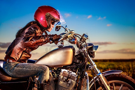 骑自行车的女孩在一个皮夹克和头盔上的摩托车