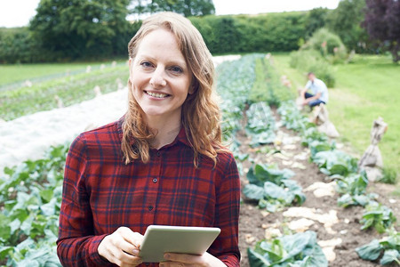 在野外使用数字平板电脑拍摄的农业女职工肖像