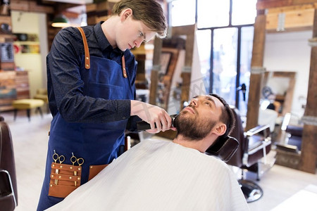 美容和人的概念-理发店的男人和理发师修剪或剃须。理发师和理发师在沙龙修剪胡子