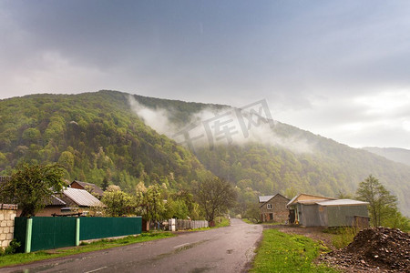 村路摄影照片_山区农村。绿色山谷中的道路和村庄。春天的风雨天气 