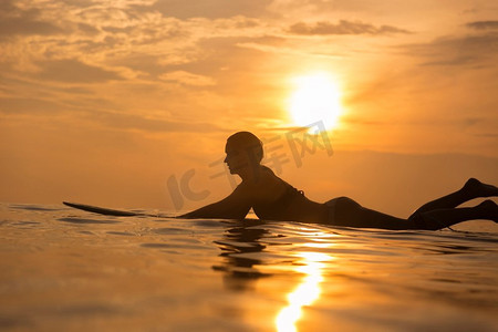 冲浪女孩在日出或日落时排队等待海浪