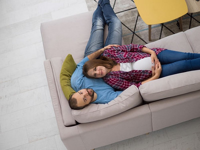 怀孕的夫妇在沙发上放松。顶视图愉快的怀孕夫妇放松在沙发在家里