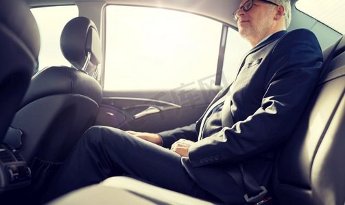 交通、出差、安全和人的概念--资深商人坐在汽车后座上。一位资深商人坐在汽车后座上