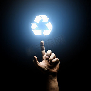绿色手指箭头摄影照片_回收概念。人类的手用手指指向回收符号
