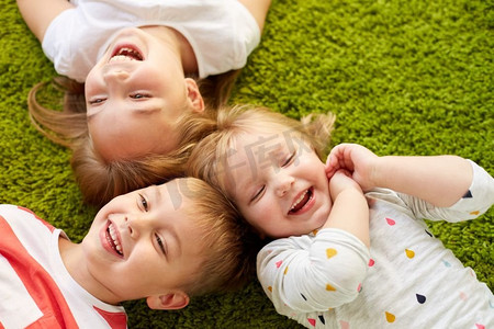 童年、休闲和家庭概念-快乐的小孩子躺在地板或地毯上。快乐的小孩子躺在地板或地毯上