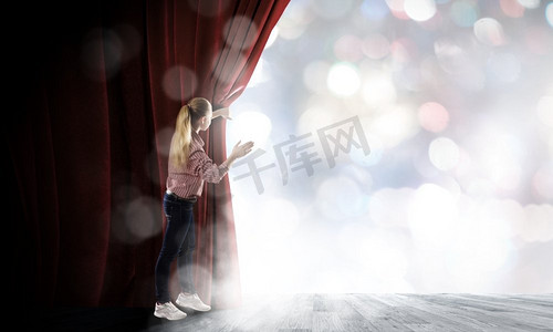 舞台上的女人。穿着随意拉开的红色窗帘的年轻女子