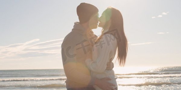 在美丽的秋日，凉爽的情侣在海滩前欢笑拥抱
