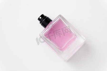 纯色浅粉色摄影照片_香水和香气概念-白色背景下的香水或粉色化妆水。一瓶香水或粉色化妆水