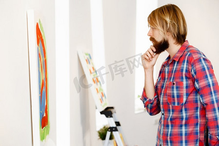 男子站在画廊和考虑艺术品。男子站在画廊和考虑抽象艺术品