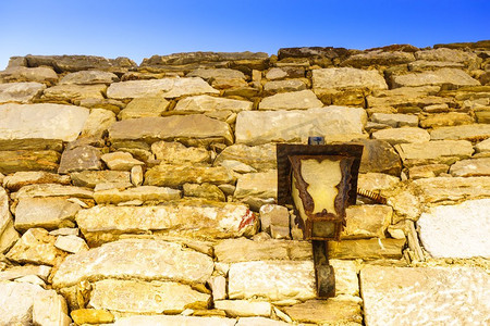 一个古老的，古老的，中世纪的灯在棕色的石头砖墙。希腊文化的建筑细节老灯在棕色石砖墙